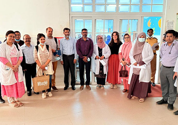 Participants at the 4th round table on cardiopulmonary resuscitation standing and sitting in front of the Les Pensières building surrounded by trees.
