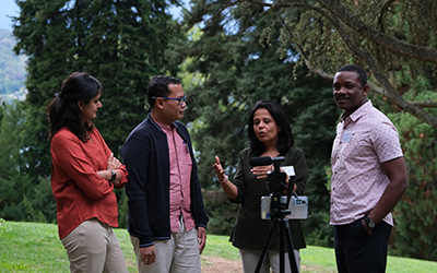 4 participants recording themselves with a camera (placed on a table) for a workshop in a park. Trees in the background