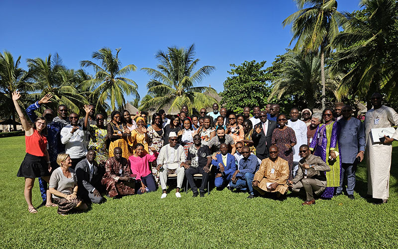 Afro-ACDx participants standing on grass, with trees on both sides and blue sky in the background