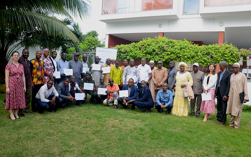 Photo de groupe des participants de la cérémonie de clôture GLLP. Certains participants ont un diplôme dans la main. Photo prise dans un jardin, le groupe est dans l'herbe