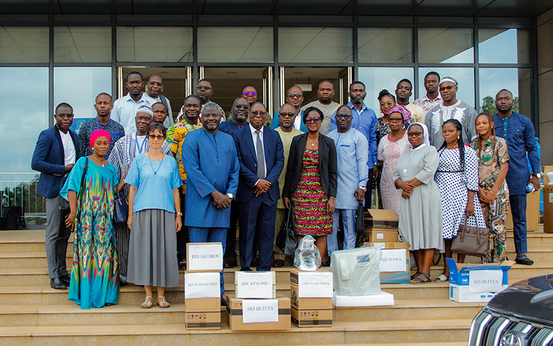 Group photo in front of a building. The group is on the steps. At their feet are laboratory equipment and materials.