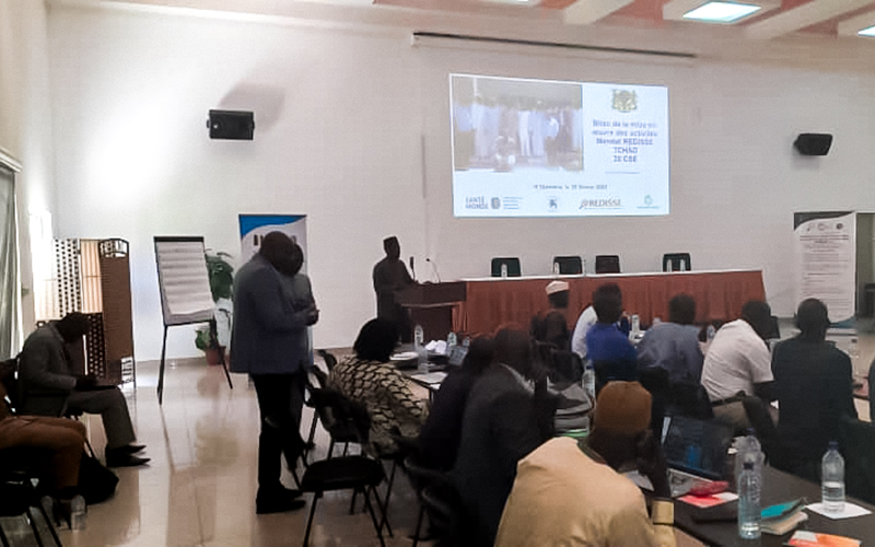 Photo taken in a room during the REDISSE Chad project feedback workshop. People are sitting on chairs, and there is a presentation projected on the wall.