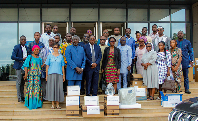 Participants in front of a building on the steps. At their feet are laboratory equipment and materials.