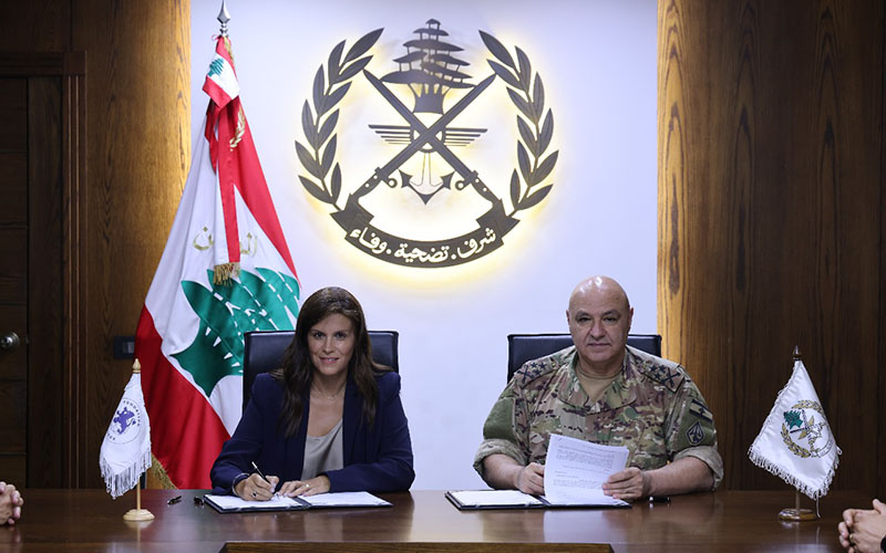 Dr Josette Najjar et Général Joseph Aoun are sitting next to each other, looking right into the camera while signing the agreement.
