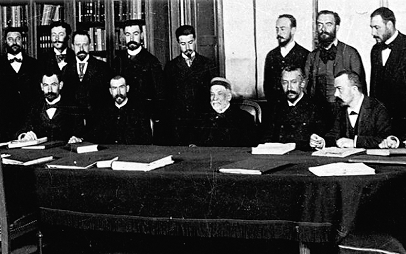 At the end of the 19th century, a group of 16 men posing around Louis Pasteur in a classroom.
