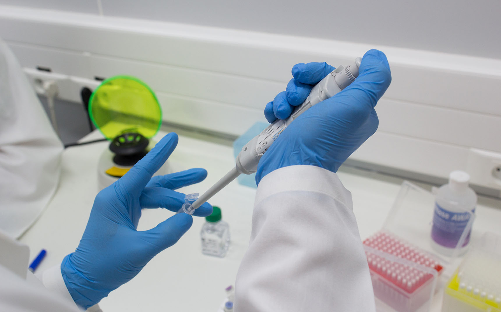 Zoom in on the hands of a lab technician handling a pipette on a bench.