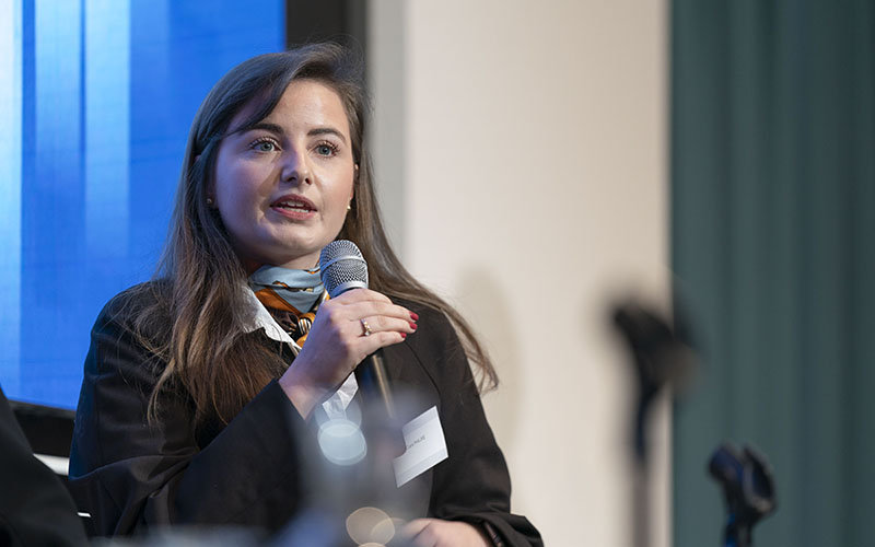 Zoom in on Clara Maure, holding a microphone.