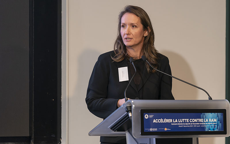 Close-up of Erta Kalanxhi standing on a desk behind a beige wall.