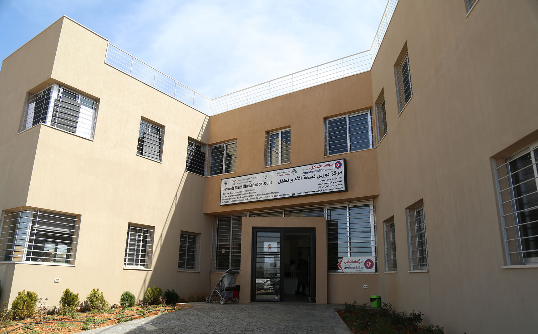 Facade of a yellow health center building with a sign written The Primary Health Center of Douris in French over the entrance.