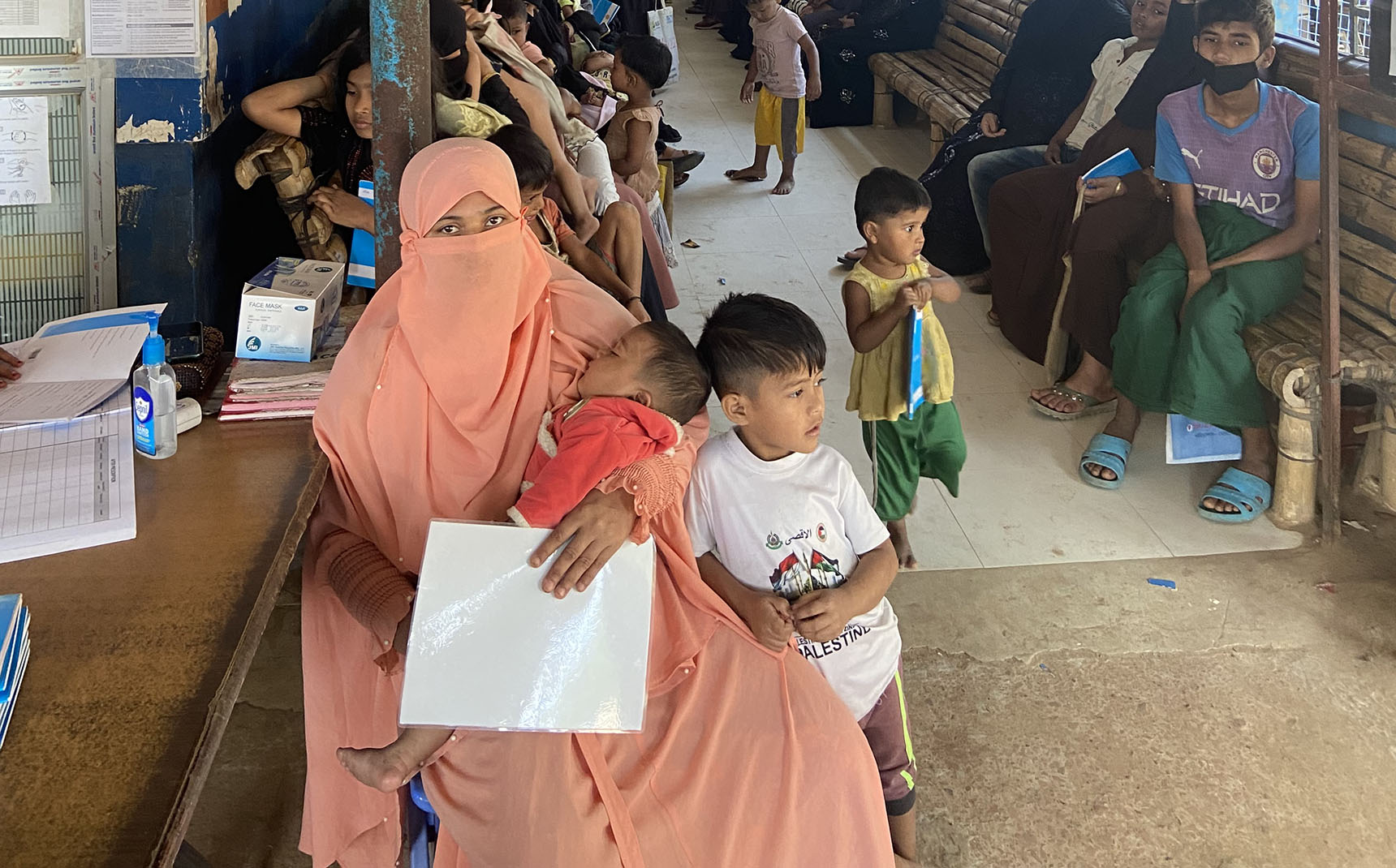 In a waiting room, women wait with their children.