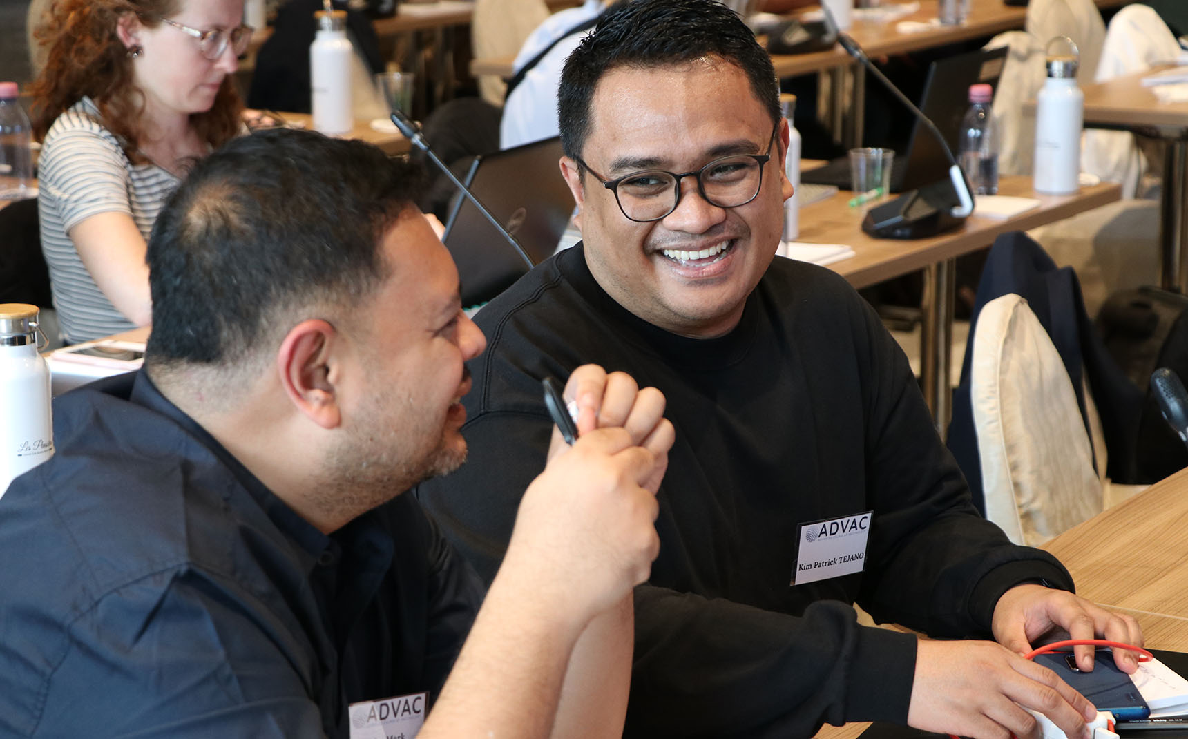 Zoom in on two people in the audience, who are smiling.