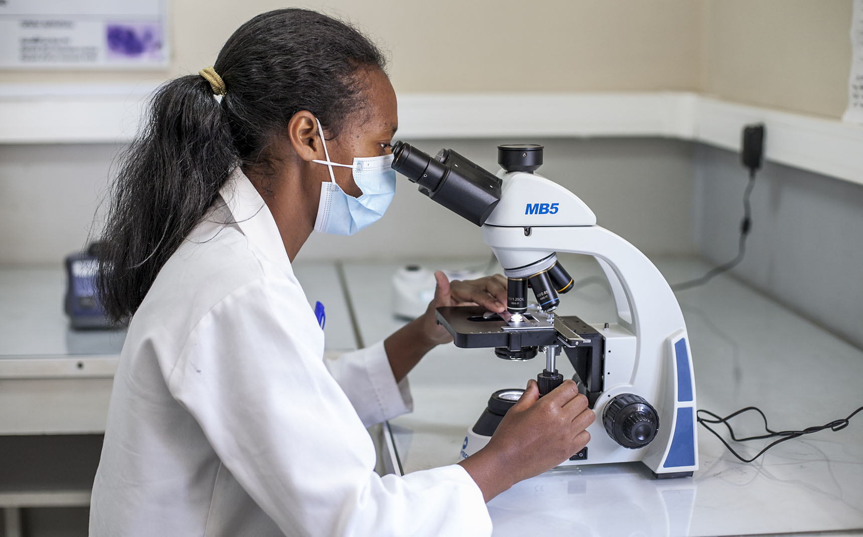 A profile lab technician uses a microscope.