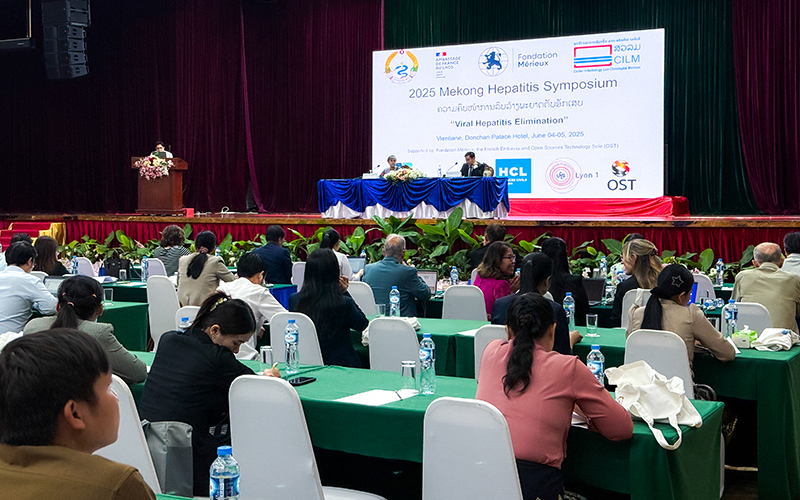 Salle de conférence avec des participants assis face à une scène lors du symposium Mékong 2025 sur l’élimination de l’hépatite, à l’hôtel Donchan Palace de Vientiane