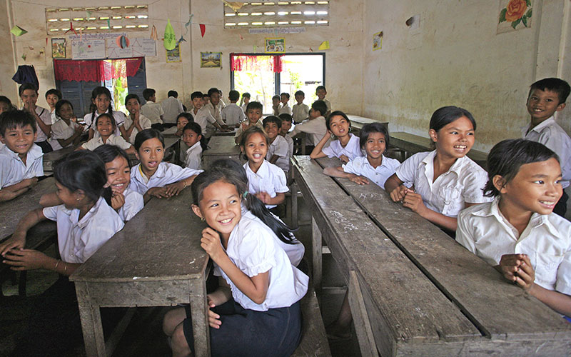 Children in uniform sitting at desks in a classroom in Cambodia 