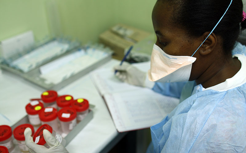 Person in blue gown handling samples in a laboratory in Haiti