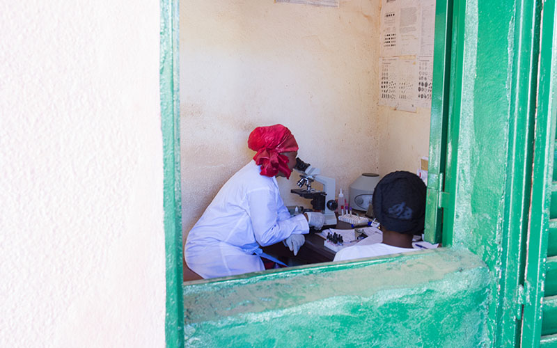 Healthcare worker using a microscope in a community health laboratory in Mali