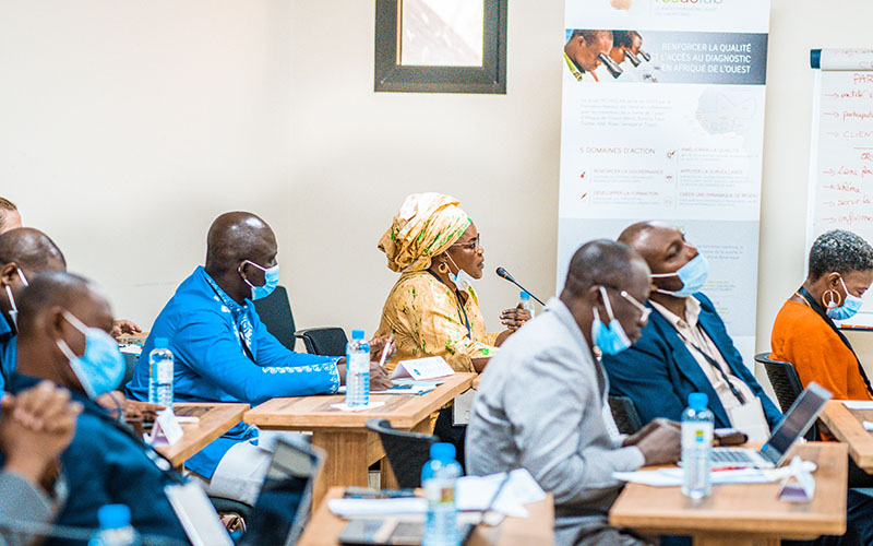 Participants seated in a conference room in Senegal, some taking notes on laptops, with a RESAOLAB banner in the background 