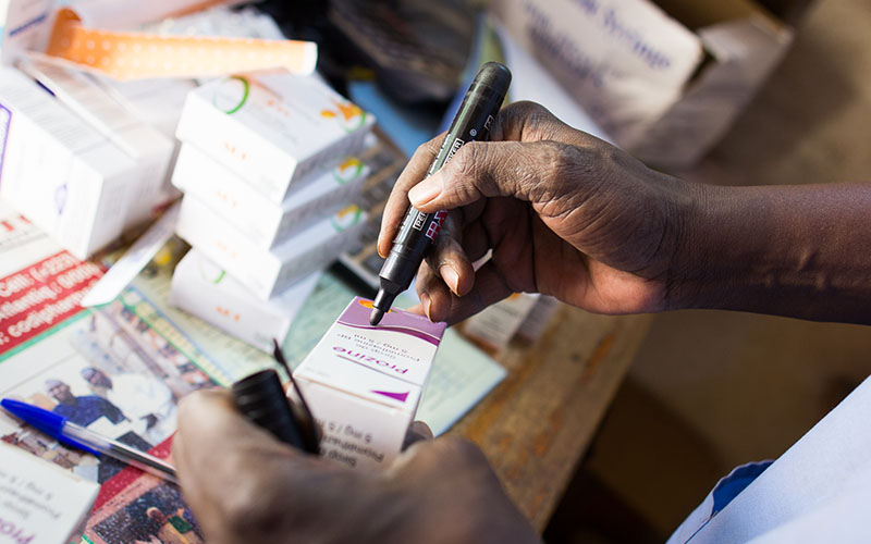 Person’s hand writing on a box of medical supplies in Togo