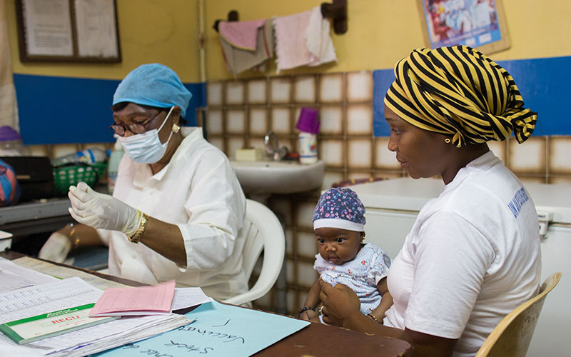 Healthcare worker consulting with a mother and her baby in a dispensary in Guinea