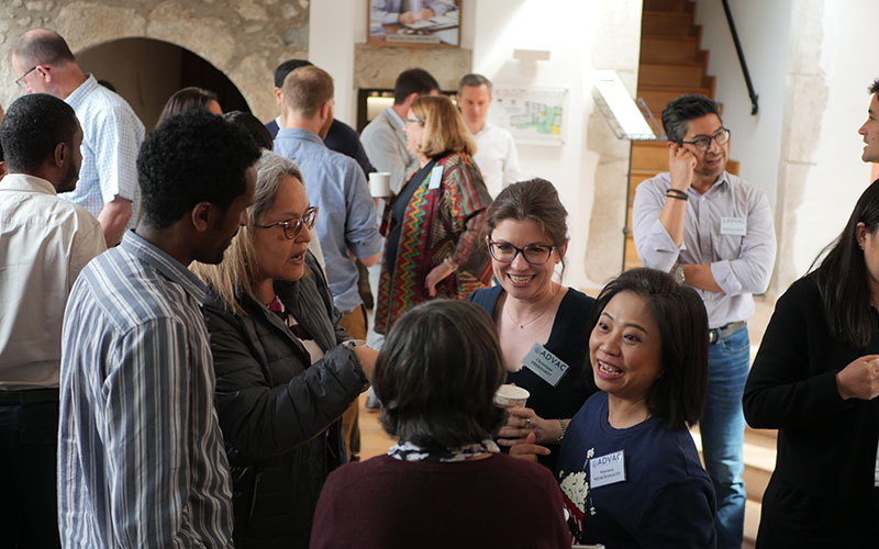 ADVAC course participants chatting during a break at the Centre des Pensières, some wearing badges and holding cups.