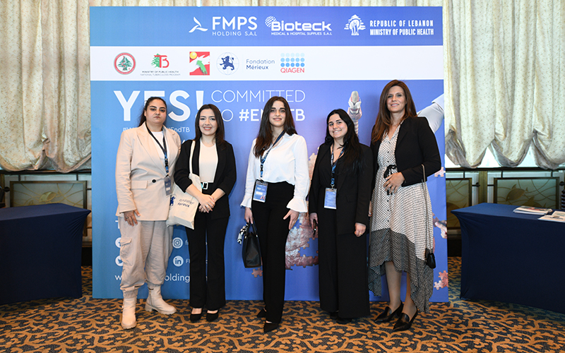 The five employees of the Mérieux Foundation in Lebanon pose in front of the event's photo backdrop.