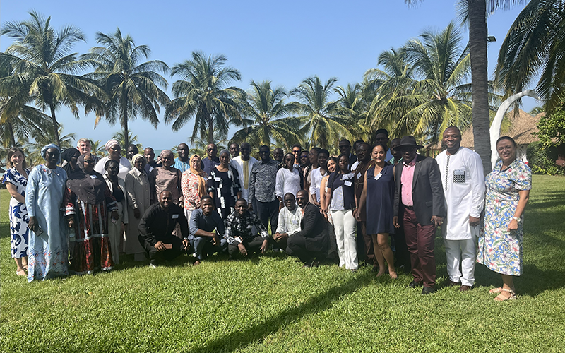 A group of Afro-ACDx participants stand in a park with palm trees.