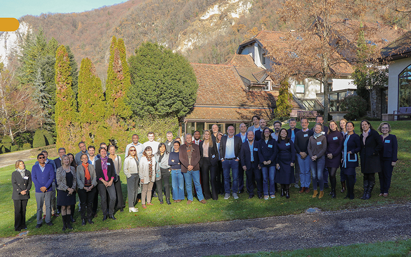 Group photo in a park, surrounded by trees and a house in the background.