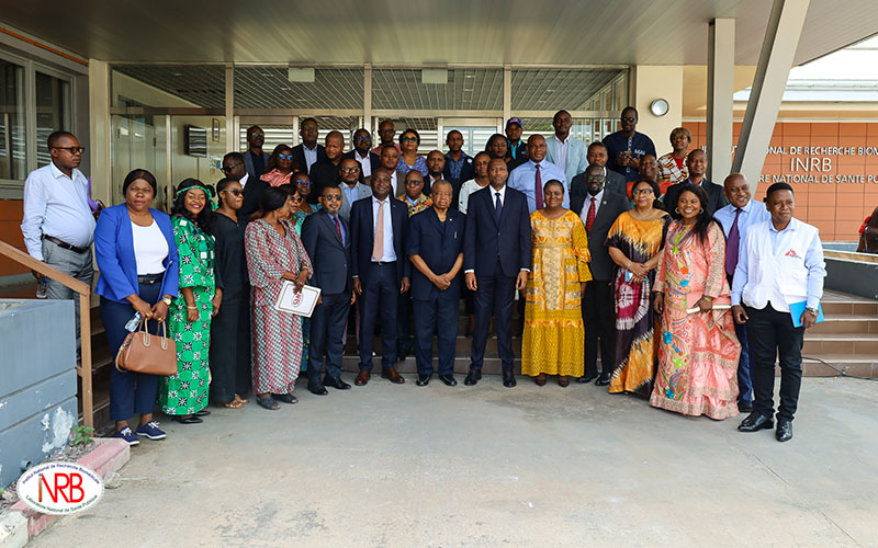 Un groupe d'une trentaine d'individus se tient debout à l'extérieur d'un bâtiment moderne